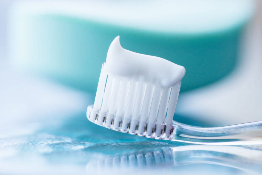 Plastic toothbrush with white toothpaste on a blue table